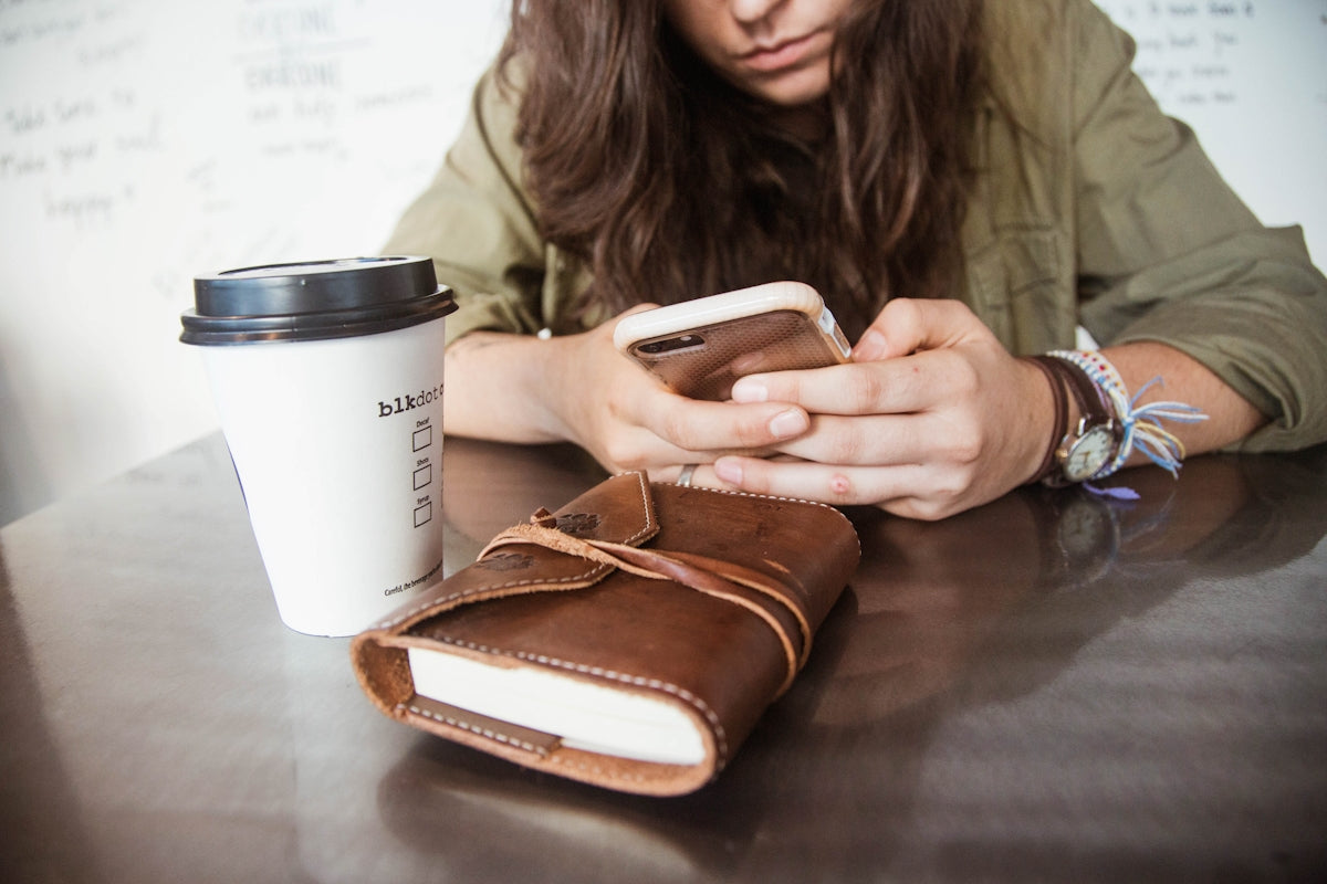woman sitting at the table while using smartphone