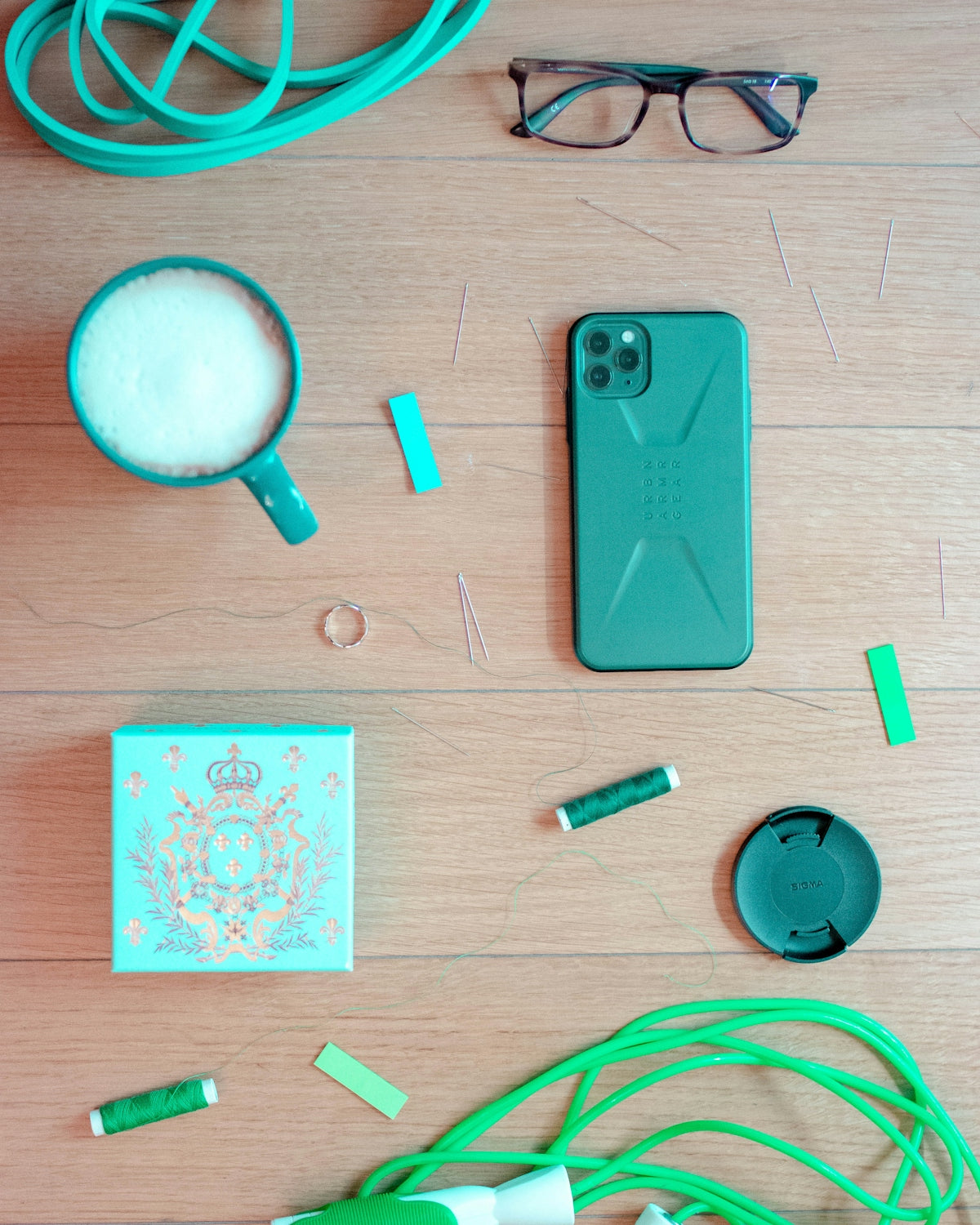 green iphone case beside pink and white earbuds and round magnifying glass