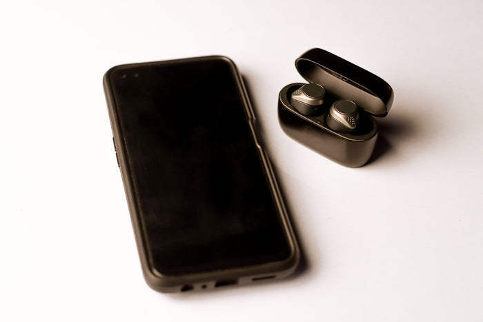 a black cell phone sitting next to a pair of ear buds