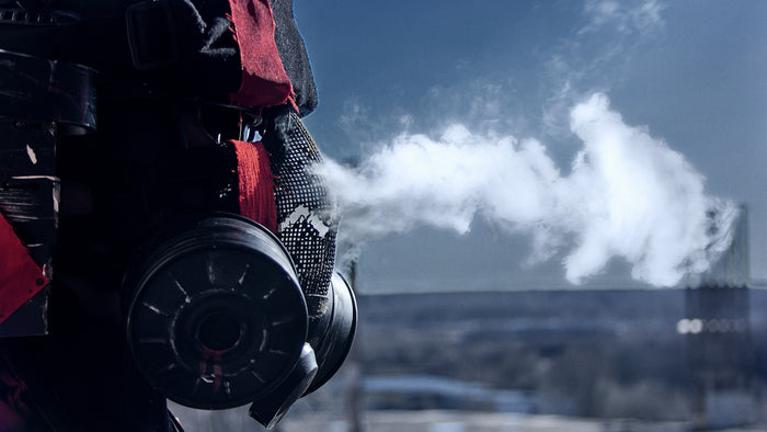 a person wearing a gas mask with a factory in the background