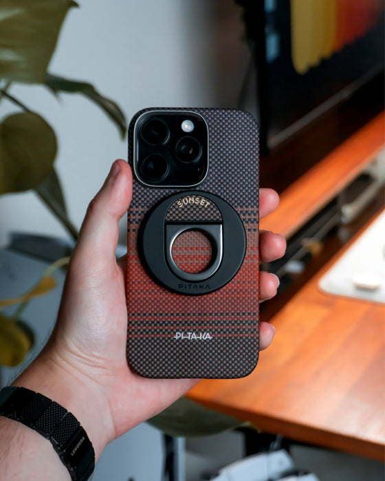 A hand holds a phone with a ring grip.