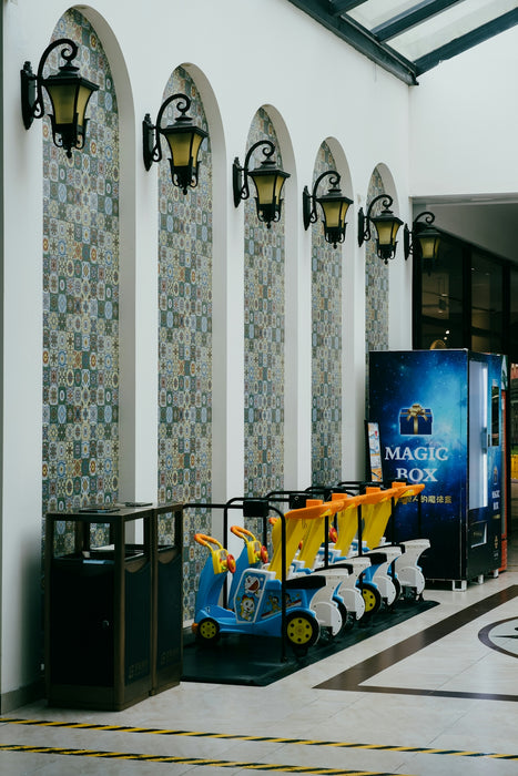 Row of kiddie rides next to a vending machine.