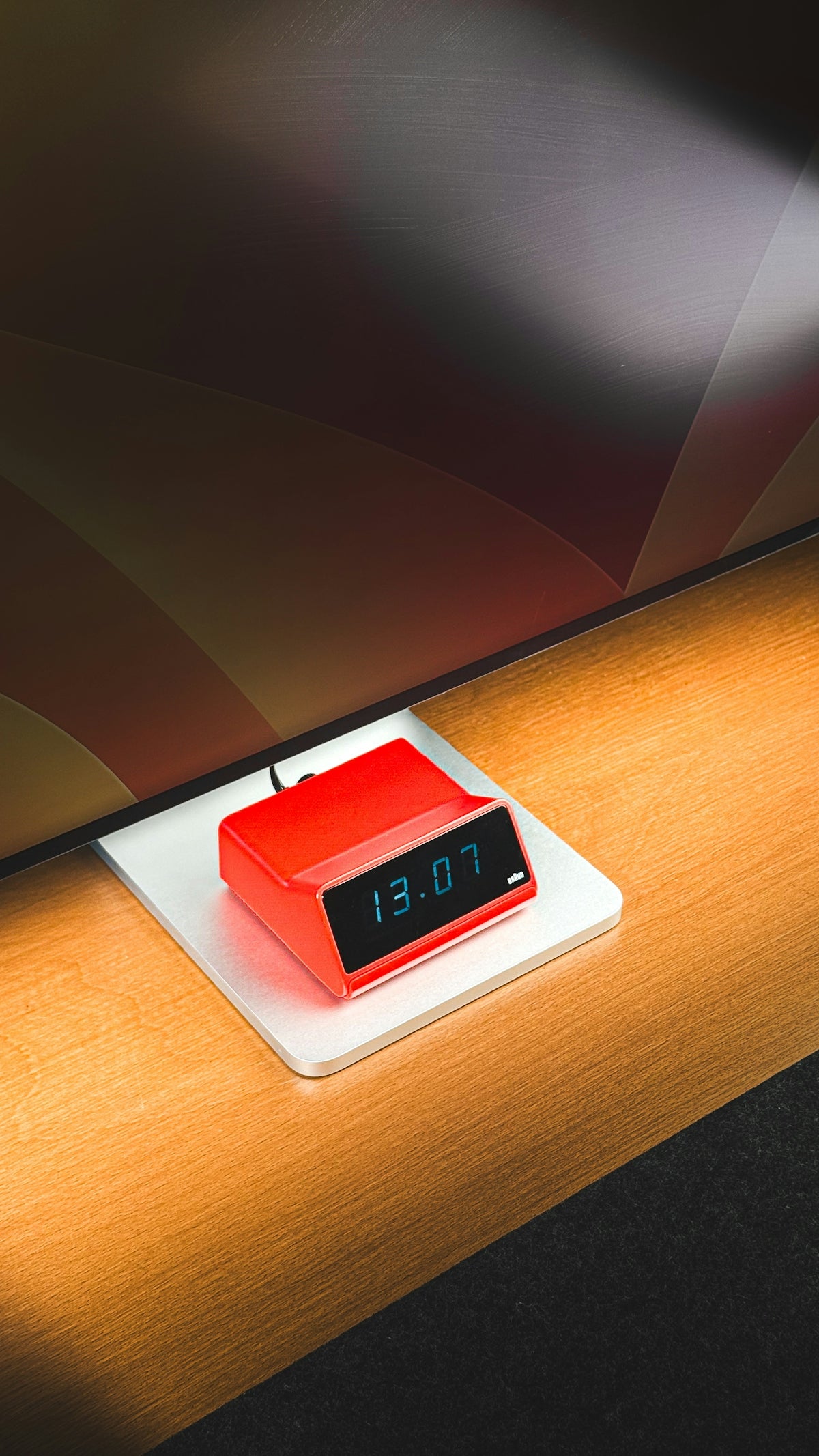 Red digital clock displaying 13:07 on a wooden desk