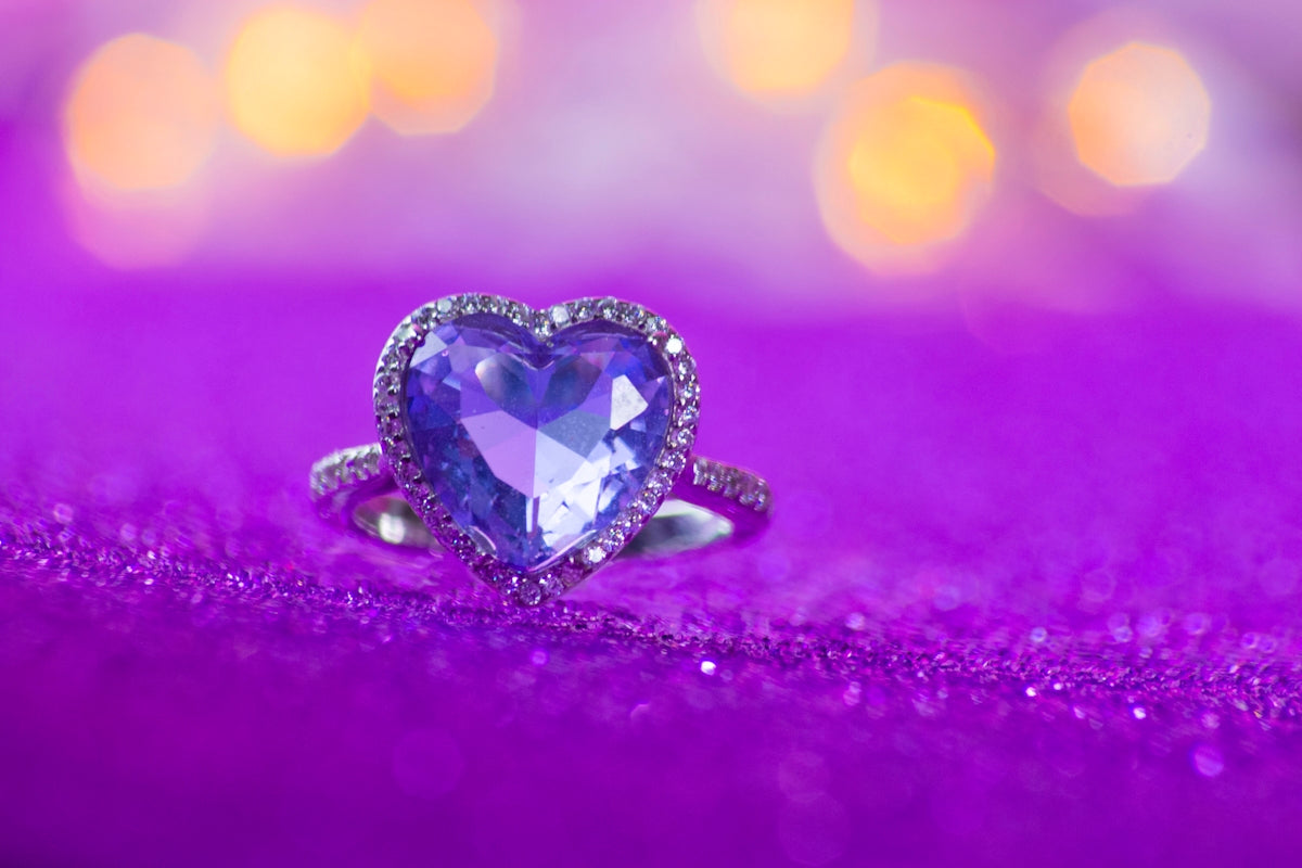 Heart-shaped purple gemstone ring on sparkly fabric