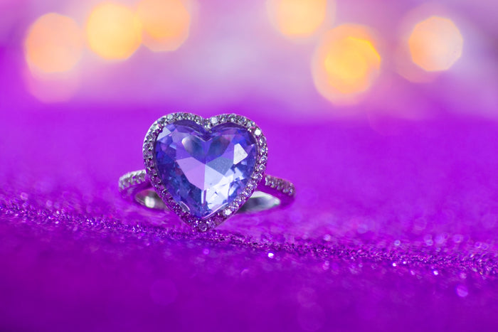 Heart-shaped purple gemstone ring on sparkly fabric